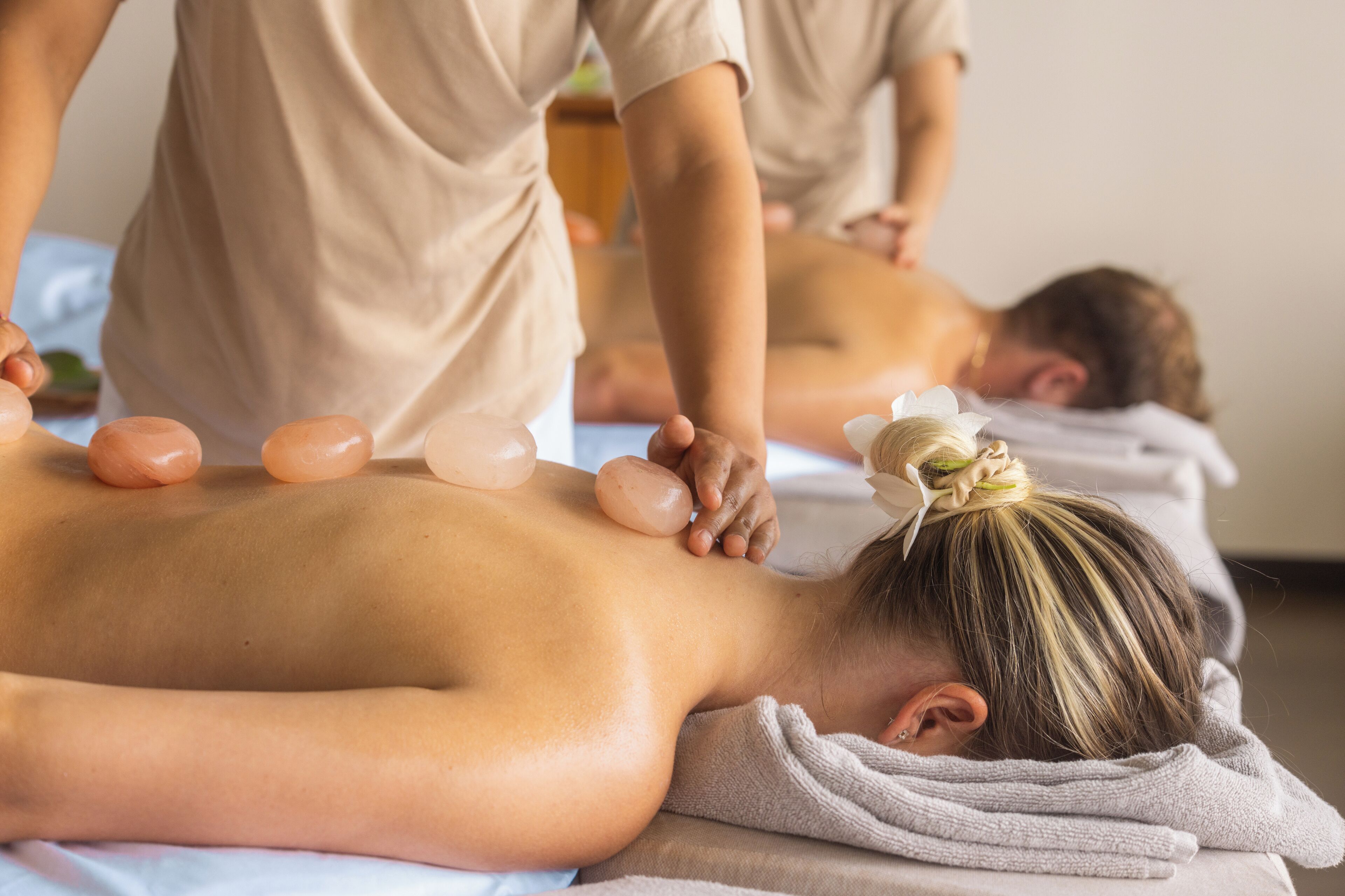 A massage therapy session with a person lying face down on a massage table, receiving a back massage.