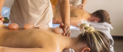 A massage therapy session with a person lying face down on a massage table, receiving a back massage.