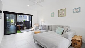 Uma sala de estar moderna com um sofá cinzento, uma mesinha redonda e um baú de madeira.