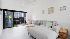 A modern living room with a grey sofa, a small round table, and a wooden chest. - Coastal Castaway - Close to the beach! (Kingscliff)