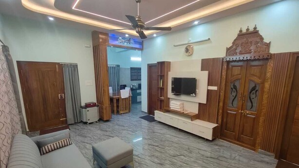 Una sala de estar moderna con sofá, reposapiés, televisor y armarios de madera.