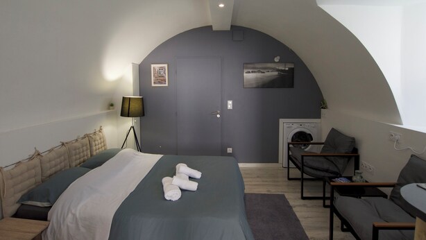 A modern bedroom with a bed, a chair, a sofa, a washing machine, and a fireplace. - Relax Studio (Jougne)