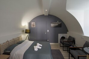 Ett modernt sovrum med en säng, en stol, en soffa, en tvättmaskin och en öppen spis.