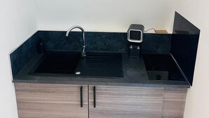 A modern kitchen with a black countertop, a sink, and a built-in stove. - Relax Studio (Jougne)