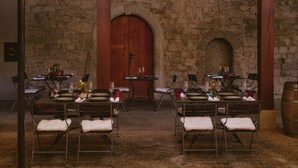 A dining area with stone walls, wooden tables, and metal chairs. - Hotel St. Petersinsel (Twann)