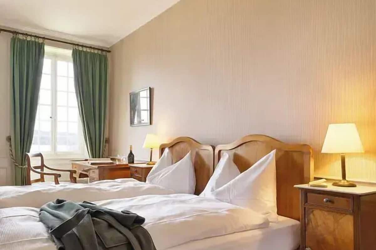 Hotellihuone, jossa on sänky, yöpöydät, työpöytä ja tuoli.