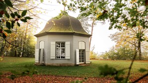 A small, single-story building with a dome roof, surrounded by a grassy area and trees. - Hotel St. Petersinsel (Twann)