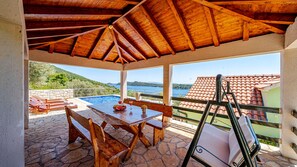 Ein überdachter Außenbereich mit Pool, Holzmöbeln und Meerblick.