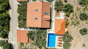 Vue aérienne d’une propriété comprenant plusieurs bâtiments, une piscine et une végétation luxuriante.
