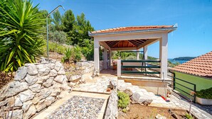 Un espace extérieur abrité, doté de murs en pierre, d’une pergola et offrant une vue sur la mer.
