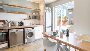 A modern kitchen with built-in appliances, a dining area with a table and chairs, and a view of the outdoor patio area. - Delightful cottage in the middle of De Waterkant with all the comforts. (Cape Town)