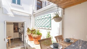 A bright kitchen with a wooden table set for dining, potted plants, and a view of the street. - Delightful cottage in the middle of De Waterkant with all the comforts. (Cape Town)