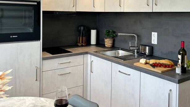 Eine moderne Küche mit einem Backofen von Bosch, einer Spüle und einem Essbereich mit Tisch und Stühlen.