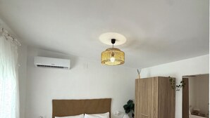 Ett sovrum med en stor säng, en garderob i trä, ett nattduksbord med en lampa och en luftkonditioneringsanläggning på väggen.