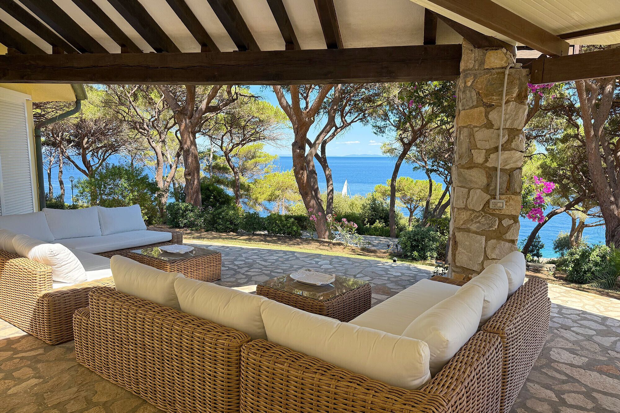 A covered outdoor seating area with wicker furniture and a stone pillar.