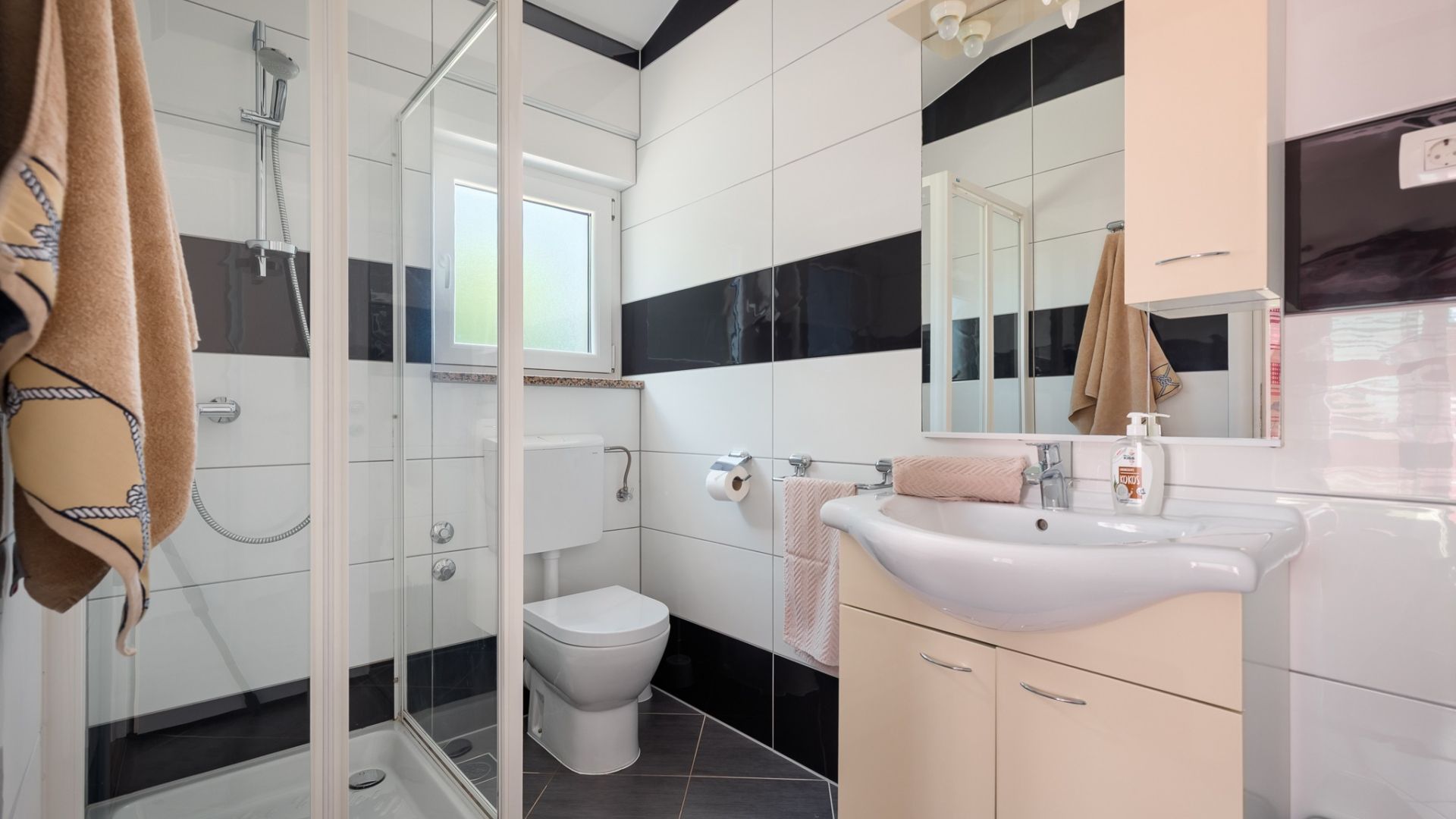 Une salle de bain moderne avec une douche à l’italienne en verre, des toilettes et un lavabo avec un miroir au-dessus.