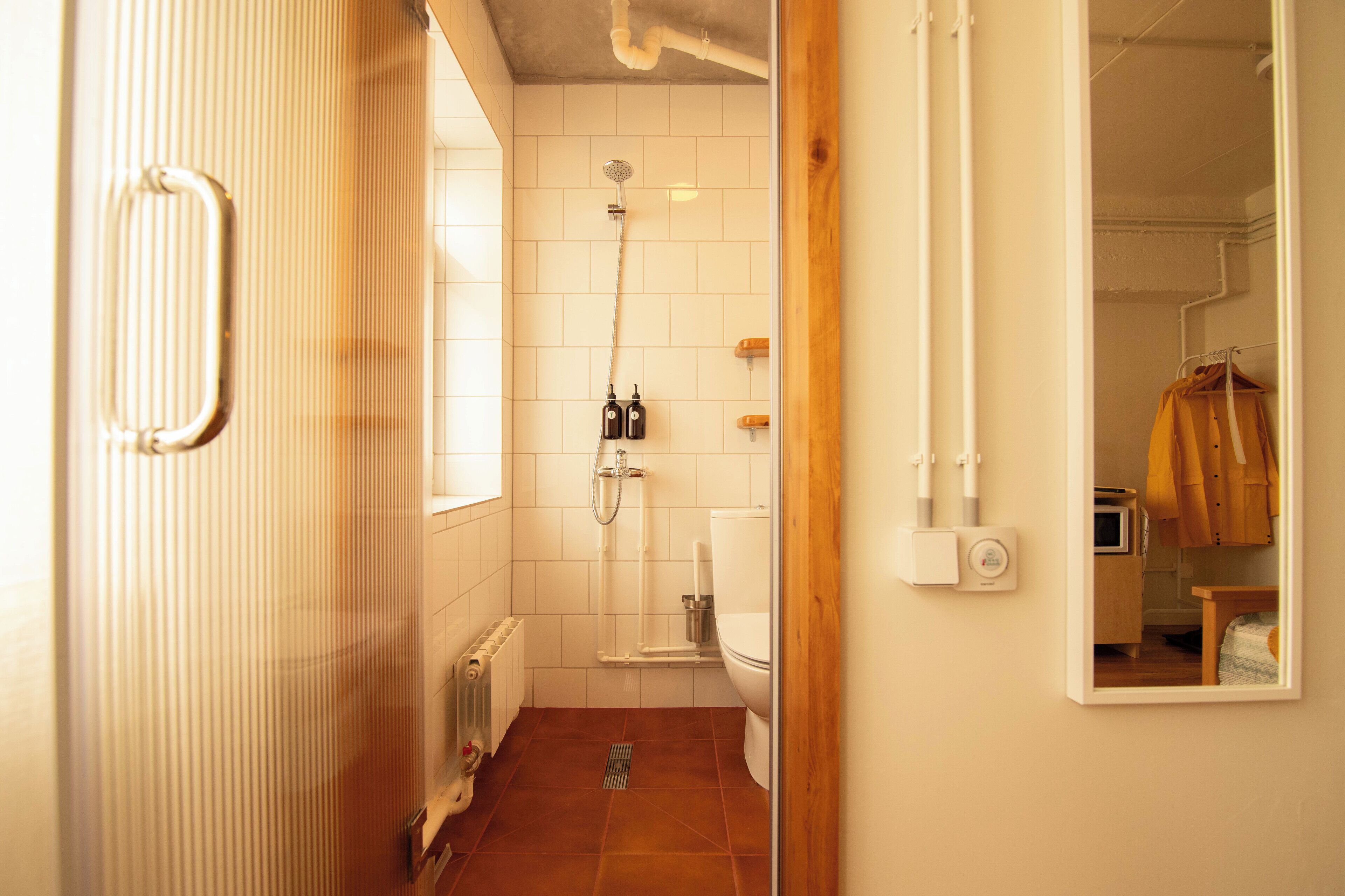 Une petite salle de bain avec une douche, des toilettes et un miroir.