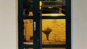 A dark green door with a glass panel, a metal handle, and a small sign on the door frame. - Urban Yurt (Almaty)