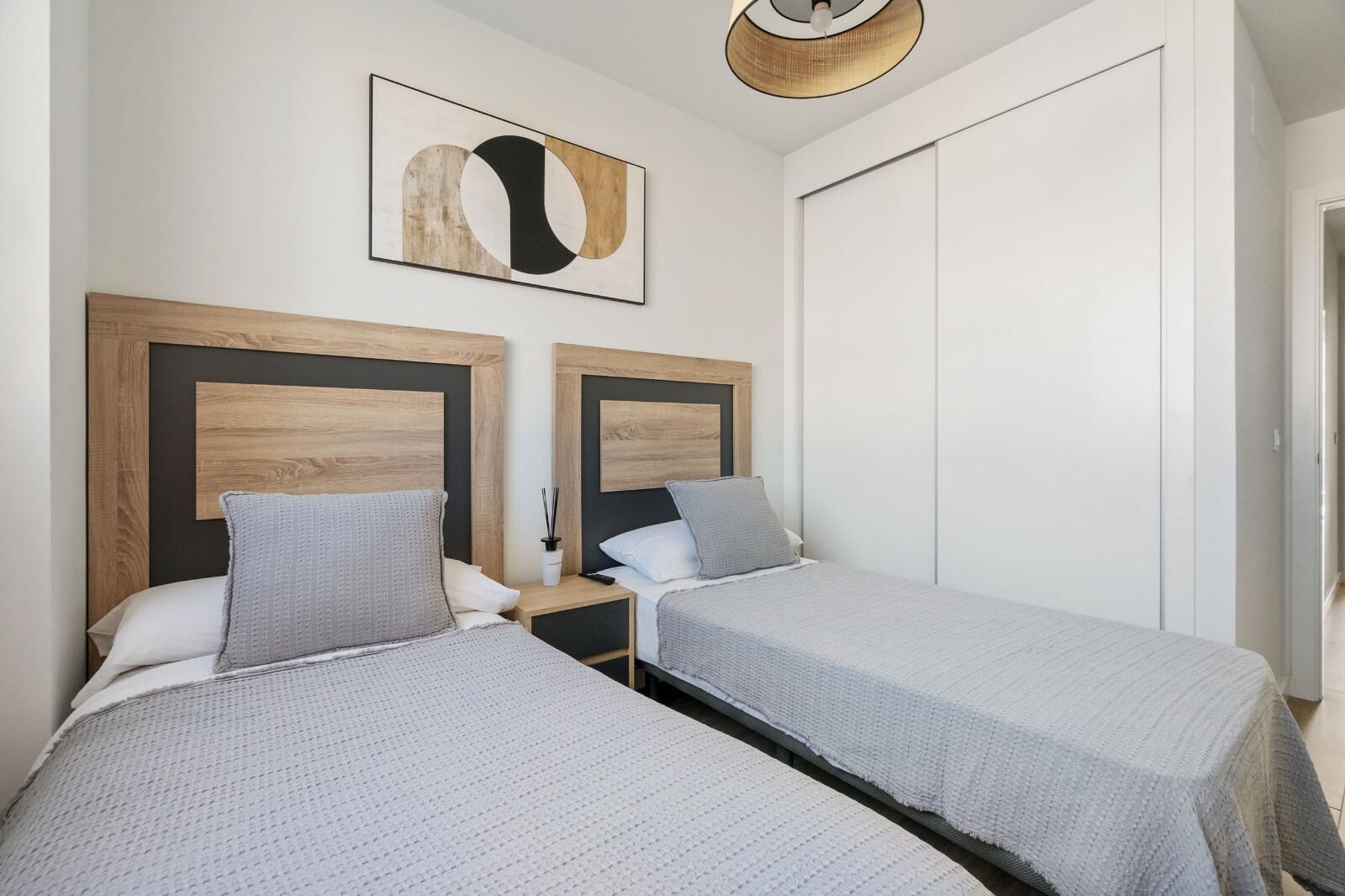 A double room with two beds, each with a wooden headboard and grey bedding.