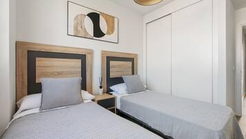 A double room with two beds, each with a wooden headboard and grey bedding.