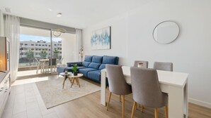 Ein modernes Wohnzimmer mit einer Couch, einem Esstisch und Stühlen. Ein großes Fenster bietet Blick auf die Stadt.