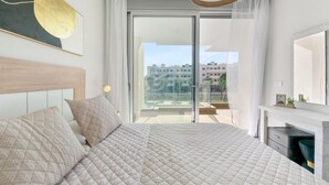 Ein modernes Schlafzimmer mit einem großen Bett, einem Kamin und einem Balkon mit Blick auf die Stadt.