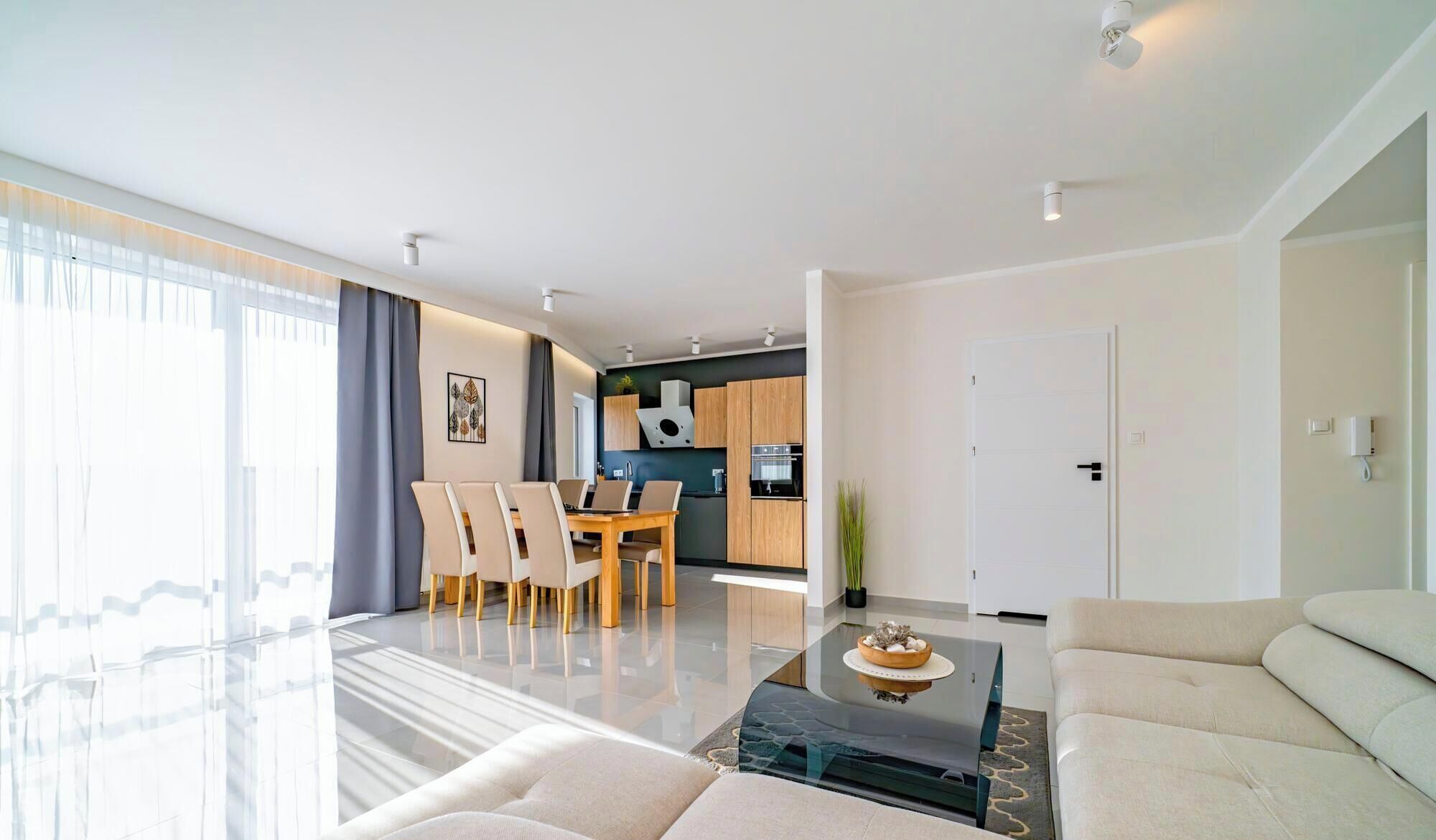 Una sala moderna con una mesa de centro de vidrio, un sofá y una zona de comedor con sillas y una mesa.
