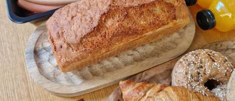 Un buffet de petit-déjeuner proposant une variété d’aliments, notamment du pain, des viennoiseries et une boisson au café.