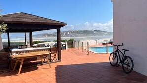 Eine Terrasse mit Holztisch und -stühlen, einem Pool und einem Fahrrad.