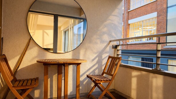 A balcony with a round mirror, wooden table, and two chairs. - Still Life Clerkenwell Executive (London)
