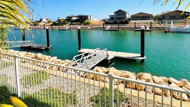 A marina with docked boats, a small pier, and houses in the background. - Haven 24 - Marina Home (Exmouth)