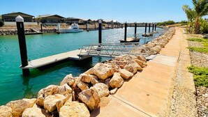 A marina with docks, a concrete walkway, and a row of rocks. - Haven 24 - Marina Home (Exmouth)