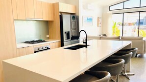 A modern kitchen with a central island, bar stools, and a large window. - Haven 24 - Marina Home (Exmouth)
