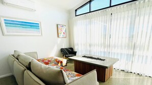 A living room with a sofa, a coffee table, a chair, and a large window with sheer curtains. - Haven 24 - Marina Home (Exmouth)