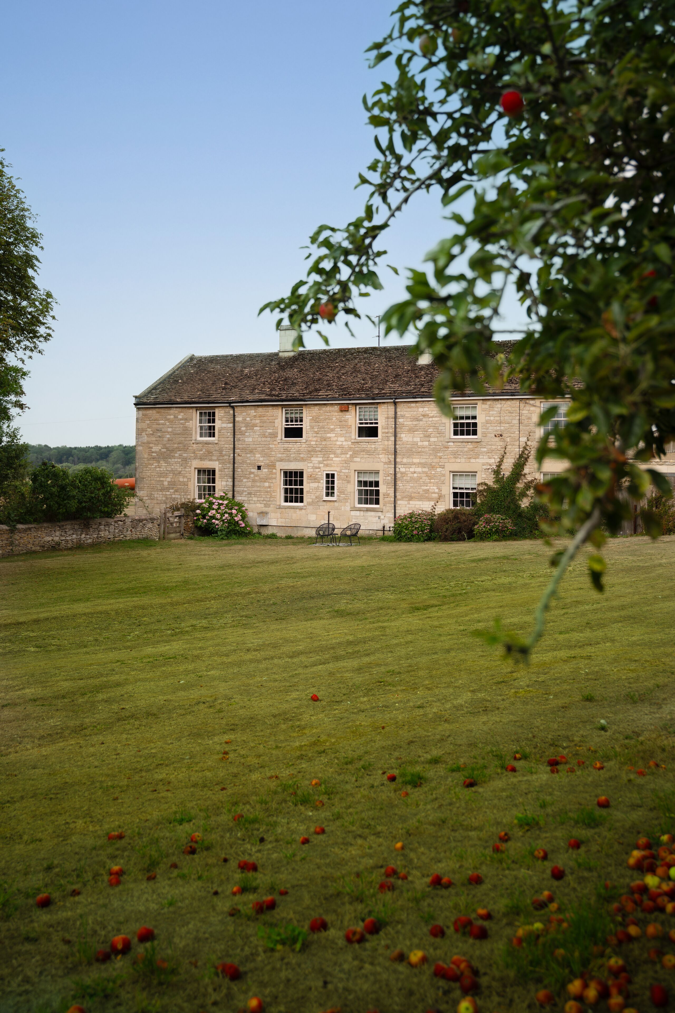 A stone building with multiple windows and a lawn in the foreground.