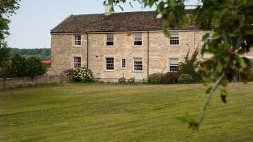 A stone building with multiple windows and a lawn in the foreground.