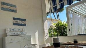Una habitación con una mesa y sillas, una ventana que da a vistas de vegetación, y carteles en la pared que dicen “TIME TO RELAX” y “WELCOME”.
