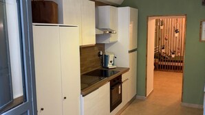 A modern kitchen with white cabinets, a built-in oven, and a countertop with a coffee machine. - Metro Hause (Napoli)