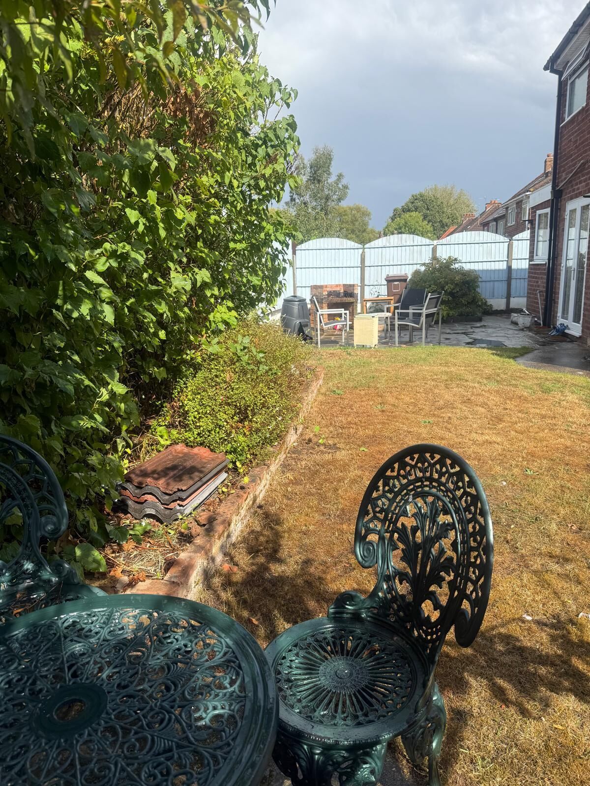 A garden with a patio area, including metal chairs and a table.