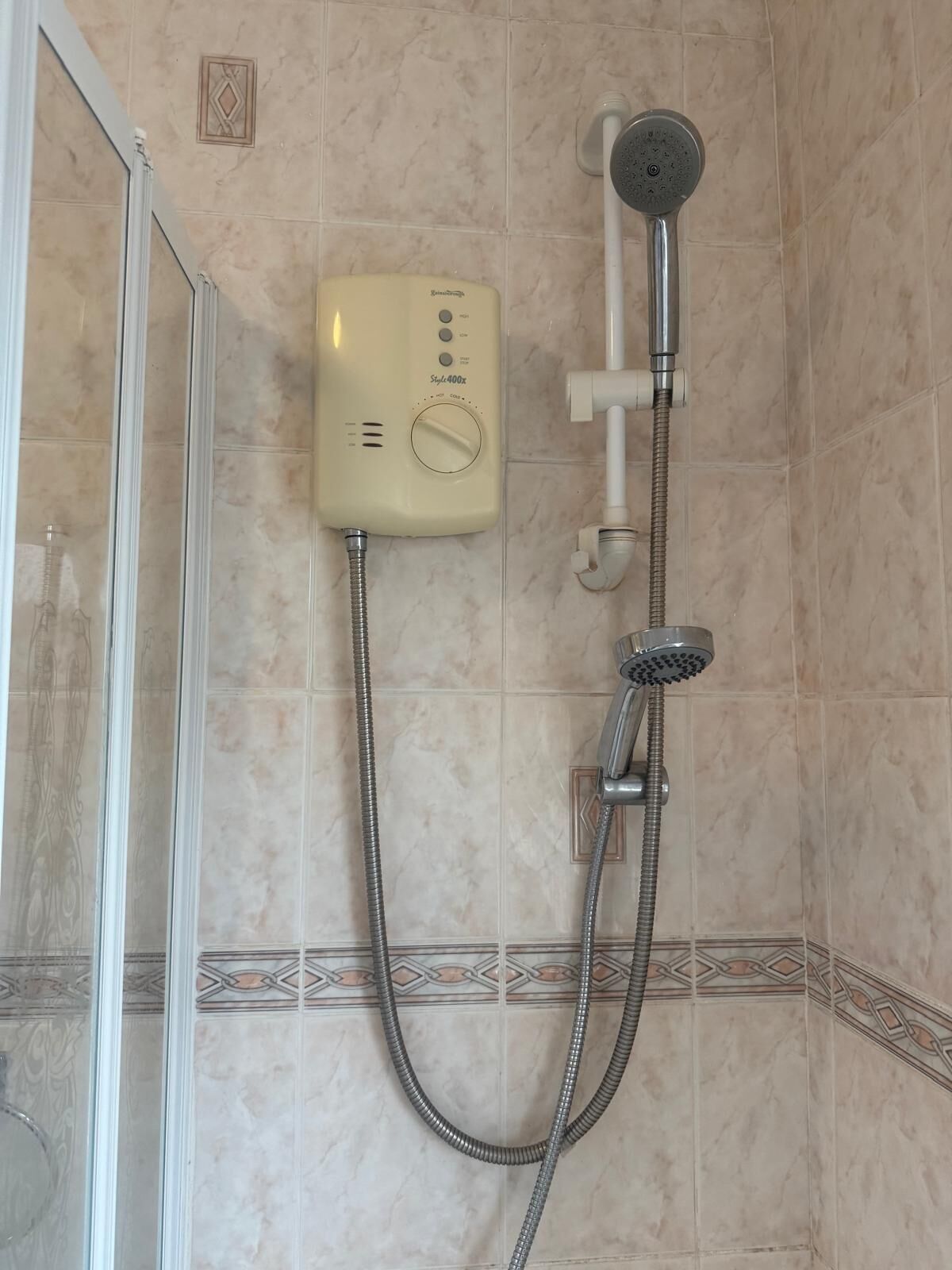 A bathroom with a shower, a control panel, and tiled walls.