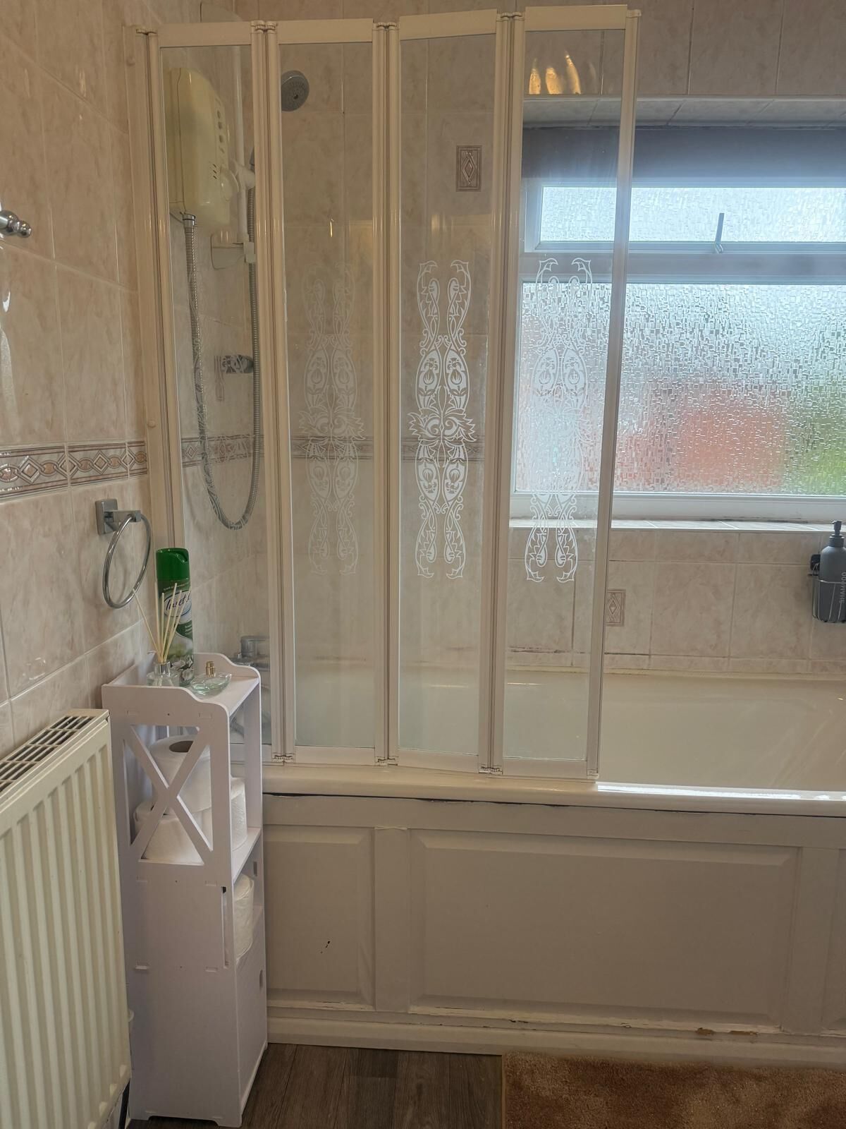A bathroom with a shower enclosure, a bathtub, and a window with frosted glass.