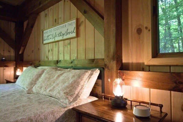 Ein Holzblockhaus-Interieur mit einem Bett, einem Wandschild und einem Tisch mit einer Laterne.