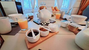 A breakfast table with various breakfast items including a teapot, cups, bowls, and a glass of orange juice. - COSY CHAMBER - Air-conditioned SUITE (Sancoins)