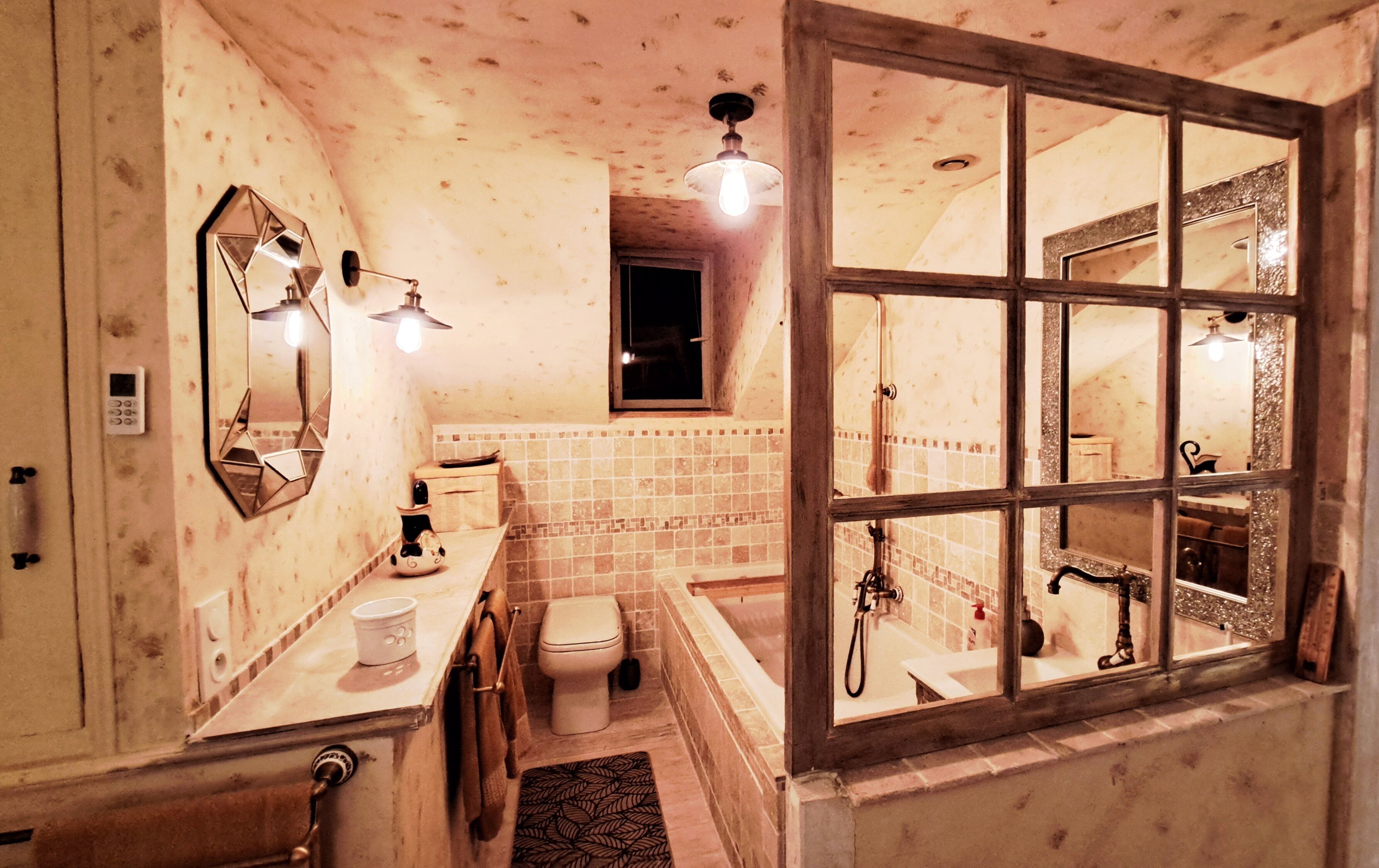 Ein Badezimmer mit Toilette, Waschbecken und Badewanne. Ein Fenster bietet Blick ins Freie.