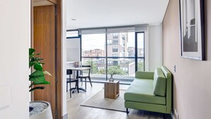 Een moderne woonkamer met een groene bank, een houten salontafel en een eethoek met een tafel en stoelen.