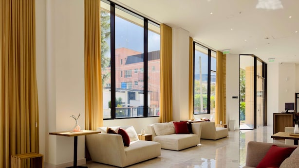 A modern hotel lobby with large windows, a seating area with sofas, and a small table with a vase. - w Unfailing Loft w Balcony in Santa B Rbara (Bogotá)