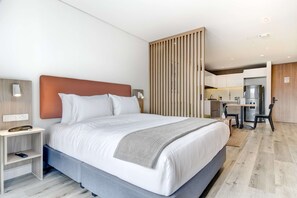 A modern hotel room with a large bed, bedside tables, a desk, and a kitchenette. - w Sparkling Loft w Balcony in Santa Barbara (Bogotá)
