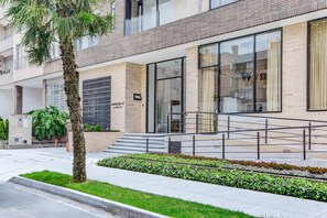 A modern building with a glass entrance, a staircase leading to the entrance, and a well-maintained garden area. - w Dreamlike 2BR w Balcony in Santa Barbara (Bogotá)