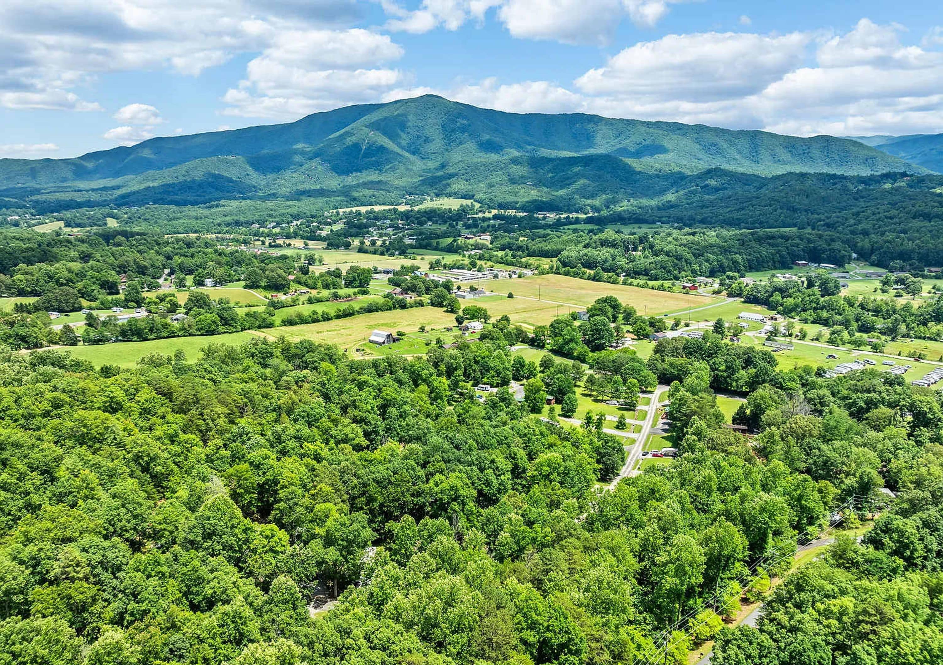 A rural landscape with a mix of residential areas, open fields, and dense forests.