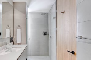 A modern bathroom with a large mirror, two sinks, a shower, and a wooden door. - w Lovely Loft w Balcony in Santa B Rbara (Bogotá)